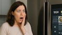 Frau steht schockiert vor ihrem smarten Kühlschrank