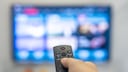 Person richtet Fernbedienung auf Fernseher