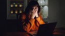 Frau sitzt mit vorgeschlagenen H&auml;nden am Laptop