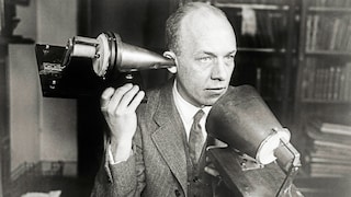 Mann telefoniert mit einem von Alexander Graham Bell entwickelten Telefonapparat