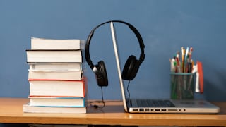 kopfhörer auf Laptop mit Bücherstapel