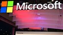 Logo und Schriftzug von Microsoft mit bunten Lichtern im Hintergrund