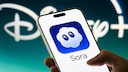 Smartphone mit Sora Logo und Disney Logo im Hintergrund