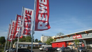 Fahnen mit Rewe-Schriftzug vor einem Rewe-Markt