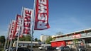Fahnen mit Rewe-Schriftzug vor einem Rewe-Markt