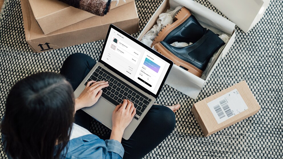 Frau mit Computer auf schoß. Schuhkartons auf dem Boden.