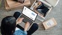 Frau mit Computer auf schoß. Schuhkartons auf dem Boden.