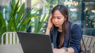 Frau mit gestresstem Gesichtsausdruck sitz vor Laptop