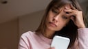 Frau schaut entnervt auf ihr Smartphone