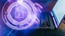 Hände die auf Computer tippen mit Sicherheitssymbol im Vordergrund