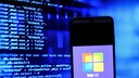 Smartphone mit Windows Logo und Codes im Hintergrund