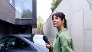 Frau die E AUto auflädt