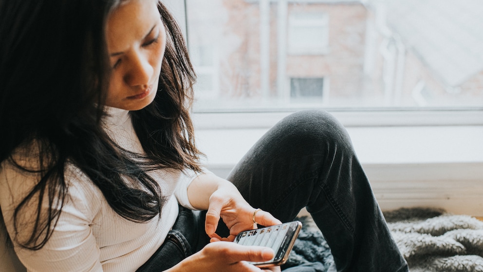 Frau schaut besorgt auf ihr Smartphone