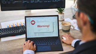 Mann an PC mit Warnung