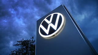 Das Volkswagen-Logo auf einer Steele vor dunklem Himmel.