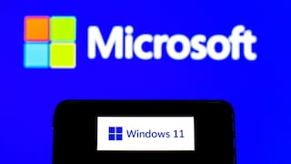 Smartphone zeigt Windows-11-Schriftzug vor Hintergrund mit Microsoft-Schriftzug