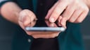Mann mit Smartphone in der Hand und einem Finger auf dem Display.