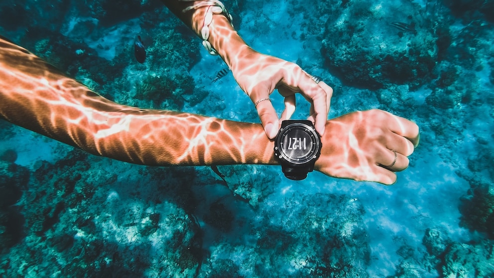 Person bedient eine Smartwatch unter Wasser