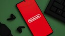 Smartphone mit Nintendo-Logo neben Tastatur und losen Earbuds