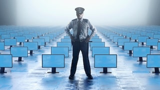 Polizist steht in einem Raum voller Computermonitore