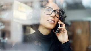 Frau steht telefonierend am Fenster.