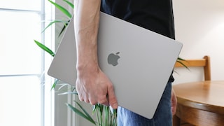 Mann trägt MacBook unter dem Arm