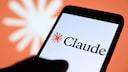 Smartphone mit Claude-Schriftzug, im Huntergrund das Claude-Logo.