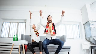 Jubelnde Deutschland-Fans auf einer Couch.
