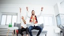 Jubelnde Deutschland-Fans auf einer Couch.