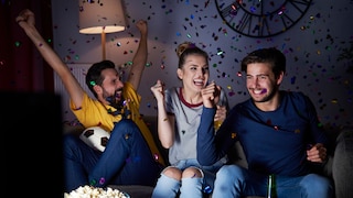 Freundesgruppe jubelt auf der Couch.