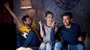 Freundesgruppe jubelt auf der Couch.
