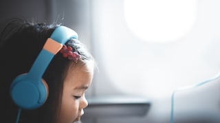 Junges Mädchen im Flugzeug mit Kopfhörern auf