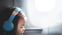 Junges M&auml;dchen im Flugzeug mit Kopfh&ouml;rern auf