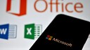 Smartphone mit Microsoft-Logo im Vordergrund. Im Hintergrund das Microsoft-Office-Logo.