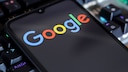 Smartphone mit Google-Logo, das auf einer Tastatur liegt.