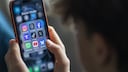 Teenager h&auml;lt ein Smartphone auf dem viel Social Media-Apps zu sehen sind.