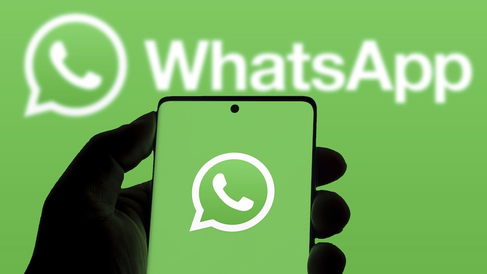 Eine Person hält ein Smartphone auf dem ein grüner Bildschirm mit dem WhatsApp-Logo zu sehen ist. Der Hintergrund ist im gleichen grün mit einem zweiten WhatsApp-Logo.