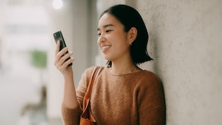 Frau schaut lächelnd auf ein Smartphone