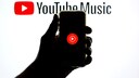 Smartphone zeigt YouTube-Music-Logo vor Hintergrund mit YouTube-Music-Schriftzug