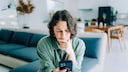 Frau mit iPhone in der Hand genervt