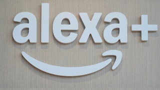 Weiße 3D-Buchstaben mit dem Schriftzug „alexa+“ sind auf einer hellen Holzfläche montiert. Unter dem Schriftzug befindet sich das geschwungene Alexa-Symbol in Weiß. Das Bild zeigt ausschließlich das Logo vor einem hellen Hintergrund aus Holz.