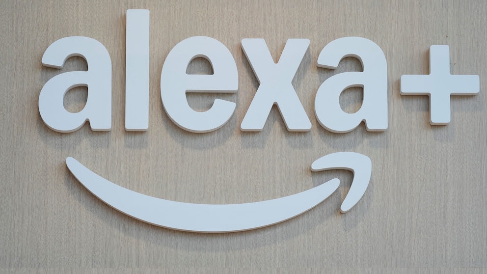 Weiße 3D-Buchstaben mit dem Schriftzug „alexa+“ sind auf einer hellen Holzfläche montiert. Unter dem Schriftzug befindet sich das geschwungene Alexa-Symbol in Weiß. Das Bild zeigt ausschließlich das Logo vor einem hellen Hintergrund aus Holz.