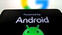 Smartphone mit &bdquo;Powered by Android&ldquo;-Schriftzug und Bugdroid, im Hintergrund Google-Logo