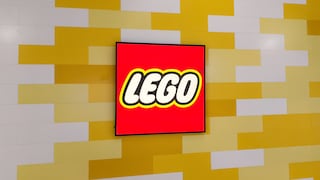 Rotes Lego-Logo auf einem rechteckigen Bildschirm vor einer Wand aus versetzt angeordneten gelben und weißen rechteckigen Elementen. Das Logo befindet sich mittig im Bild und ist von einem schwarzen Rahmen umgeben. Die Wand im Hintergrund erinnert mit ihrer Gestaltung an gestapelte Lego-Steine.
