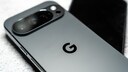 Alt-Text: Nahaufnahme eines grauen Google-Pixel-Smartphones mit sichtbarem Kameramodul und Google-Logo auf der R&uuml;ckseite, daneben liegt ein weiteres unscharfes Smartphone im Hintergrund.