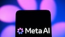 Logo von Meta AI auf einem schwarzen Smartphone-Display vor unscharfem blau-violetten Hintergrund mit leuchtenden Lichtfl&auml;chen