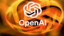 OpenAI-Logo in Wei&szlig; vor einem unscharfen Hintergrund aus orangefarbenen und gelben Lichtb&auml;ndern. Unter dem Logo steht der Schriftzug &bdquo;OpenAI&ldquo; in wei&szlig;er Schrift. Die Aufnahme ist von warmen Oranget&ouml;nen gepr&auml;gt und wirkt durch die starke Unsch&auml;rfe im Hintergrund abstrakt.