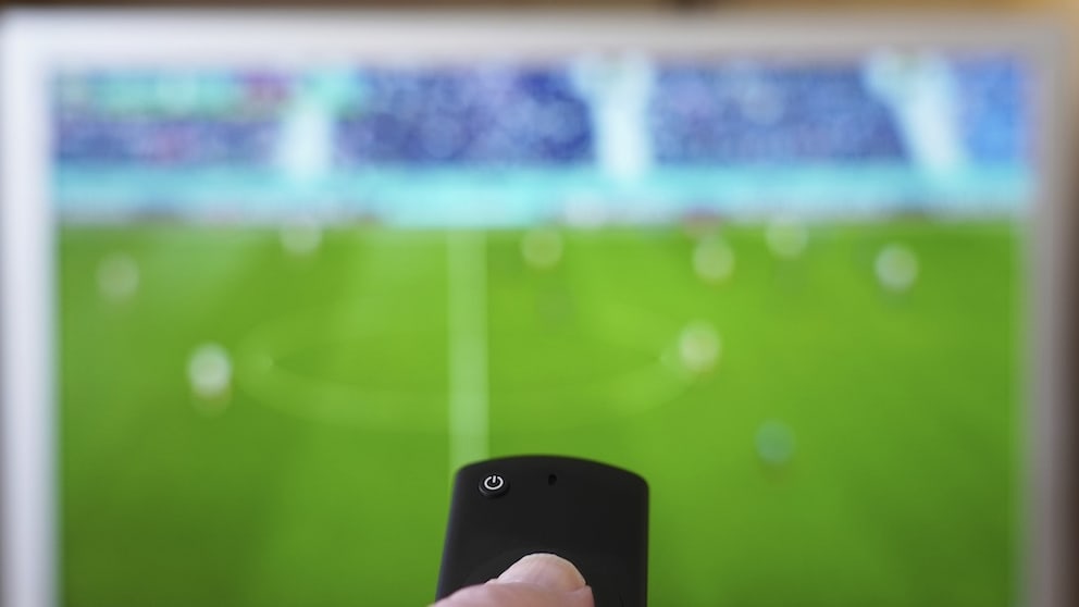 Person zeigt mit der Fernbedienung auf einen Fernseher