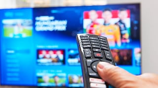 Person hält eine Fernbedienung auf einen Fernseher gerichtet