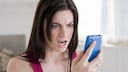 Frau schaut ver&auml;rgert auf ein Smartphone.